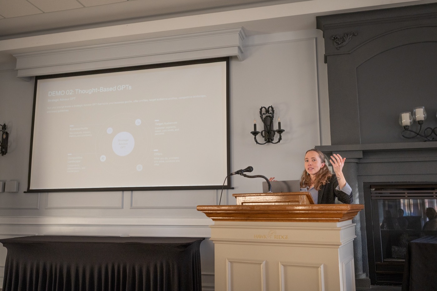 Teryl Brouillette at a podium beside a projected slide during a custom GPT workshop